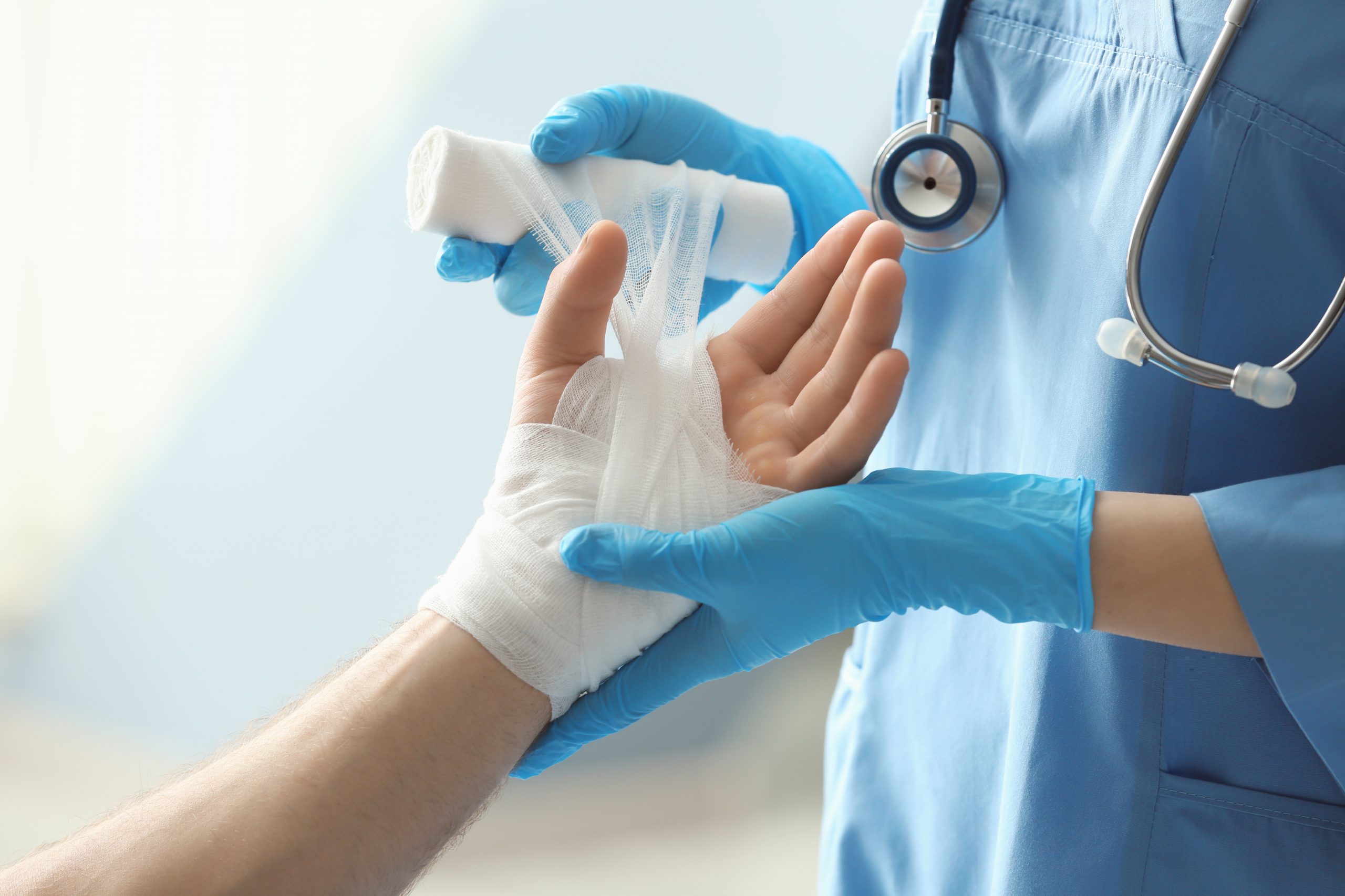 patient's hand being wrapped in bandage by a doctor